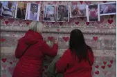  ?? ALASTAIR GRANT — THE ASSOCIATED PRESS FILE ?? Family members write a message to two sisters who died of COVID at the National Covid Memorial wall in London.