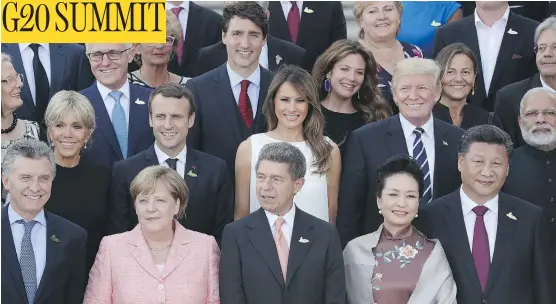  ?? SEAN GALLUP/ GETTY IMAGES) ?? World leaders and their spouses pose for a group photo on the first day of the G20 economic summit on Friday. Outside, an estimated 100,000 protesters continued demonstrat­ing against what they consider an offensive gathering of the world’s wealthiest...