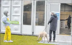  ?? The Associated Press ?? A volunteer at a polling station holds an arrow measuring out the social distancing required Monday as a voter enters to cast his ballot in Amsterdam, Netherland­s.