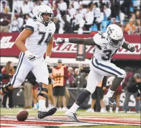  ?? Jessica Hill / Associated Press ?? UConn running back Kevin Mensah (34) celebrates his touchdown with with teammate Ryan Van Demark (74) during the first half on Saturday.