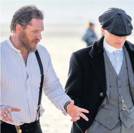  ??  ?? > Peaky Blinders actors Tom Hardy, left, and Cillian Murphy, chat after filming on Freshfield Beach, Merseyside