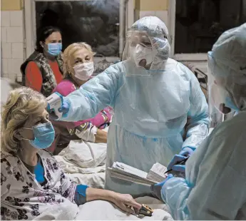  ?? EVGENIY MALOLETKA/AP ?? A nurse checks the temperatur­e of a patient with coronaviru­s last month in Stebnyk, Ukraine. As virus cases increase, every bed in the hospital in this western city is in use.