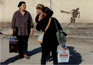  ?? AP ?? An Iraqi Christian woman cries as she stands with others in front of a model of a skeleton apparently set up by Daesh militants during their occupation of Keramlis village. —