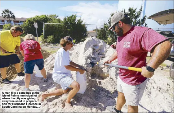 ?? AP ?? A man fills a sand bag at the Isle of Palms municipal lot where the city was giving away free sand in preparatio­n for Hurricane Florence in South Carolina on Monday.