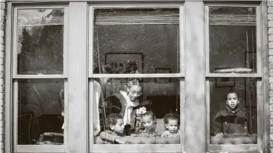  ?? Steve Gonzales / Staff photograph­er ?? A family in Third Ward tries to stay warm by playing in the sunlight coming through their front window during a power outage as temperatur­es plummeted to historic lows in the region.