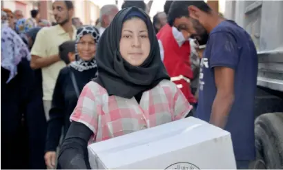  ?? AFP ?? A Syrian resident of the northeaste­rn city of Deir El Zour carries back aid parcels provided by the Syrian Red Crescent. —