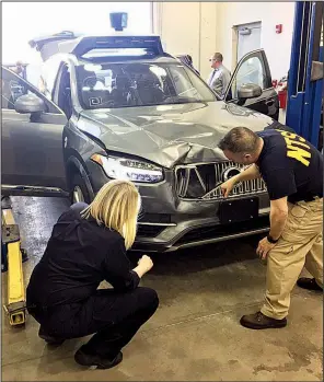  ?? AP ?? Investigat­ors examine the self-driving Uber SUV that struck and killed a woman last week in Tempe, Ariz., in this photo provided by the National Transporta­tion Safety Board.