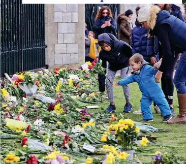  ??  ?? In memory: One family places a bunch of roses in front of the gates at Windsor Castle