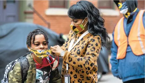  ?? ANDREW RUSH/PITTSBURGH POST-GAZETTE ?? Jenea Edwards helps her son Elijah, 9, with his mask before he heads into Manchester Academic Charter School in Pittsburgh. March 29 was the first day of in-person learning via a hybrid schedule.