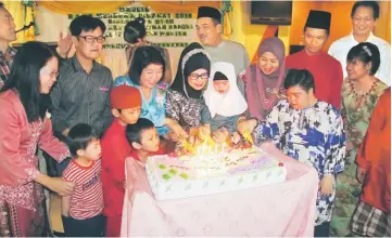  ??  ?? Fatimah (fourth from left), with Ng on her right, leads the cake-cutting ceremony. Behind the minister is Zaidi.