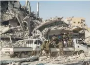  ?? THE ASSOCIATED PRESS ?? Members of the U.S.-backed Syrian Democratic Forces ride Friday near the main traffic circle in Raqqa, Syria.