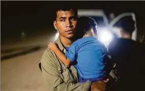  ?? Gregory Bull / Associated Press ?? A migrant from Peru holds his son as he waits to be processed by U.S. Border Patrol agents near the end of a border wall near Yuma, Ariz., on Aug. 23.