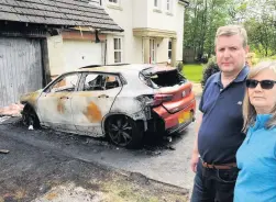  ??  ?? Torched Councillor Campbell and his wife Fiona with the charred remains of the car