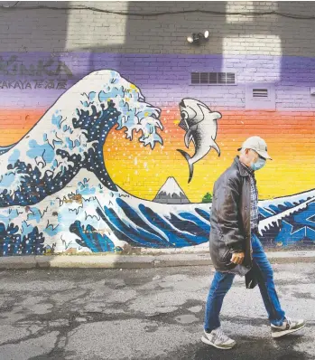  ?? PETER J THOMPSON/NATIONAL POST ?? A pedestrian passes a mural by artist Kinka Izakaya on Loretto Lane at Bloor Street in Toronto Thursday. As restrictio­ns are eased across the country, concerns are emerging about a potential second wave of COVID-19.