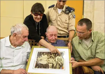  ?? ASSOCIATED PRESS ?? Holocaust survivor Eliahu Pietruszka (center) looks at a picture with Alexandre Pietruszka and family in Israel. Pietruszka, who fled Poland at the beginning of World War II and thought his entire family had perished, learned that a younger brother had...