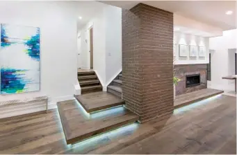  ??  ?? Natural brick clads the central pillar that separates the fireplace from stairways to children’s bedrooms and the private master suite. The tiered landing is also enhanced by LED lighting.
