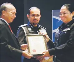  ??  ?? Masir (left) hands over Execellent Service Award to an officer while Mustafar looks on.