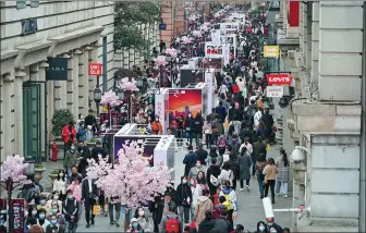  ?? ZHOU GUOQIANG / FOR CHINA DAILY ?? Visitors (above) attend a photo exhibition marking the victory of Wuhan and Hubei over the coronaviru­s along the same section of the street on Sunday.