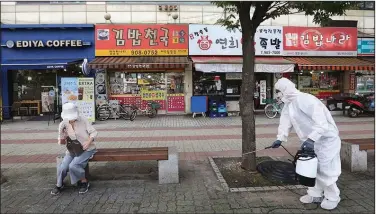  ?? (AP/Ahn Young-joon) ?? A worker sprays disinfecta­nt on a street Tuesday in Goyang, South Korea. The government is closing schools and switching back to remote learning in the area around Seoul as the country counted its 12th-straight day of triple-digit increases in coronaviru­s cases.