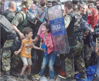  ??  ?? Children cry as migrants waiting on the Greek side of the border with the Former Yugoslav Republic of Macedonia (FYROM) break through a cordon of special police forces from the neighborin­g country to reach the city of Gevgelija.