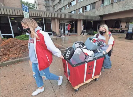  ?? MARK HOFFMAN / MILWAUKEE JOURNAL SENTINEL ?? Freshmen Lauren Tamborini and Bailey Donahue move out of Sellery Residence Hall at UW-Madison on Thursday. The students will be attending class online for at least the next two weeks. Citing rapidly rising COVID-19 cases including two straight days in which one in five student tests came back positive, University of Wisconsin-Madison Chancellor Rebecca Blank locked down the state's largest university campus for two weeks.