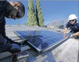  ?? Irfan Khan Los Angeles Times ?? SUNRUN WORKERS Elgin Clark, left, and Edgar Palma install a panel in Van Nuys in 2016. The U.S. will impose an initial 30% levy on cheap, imported panels.