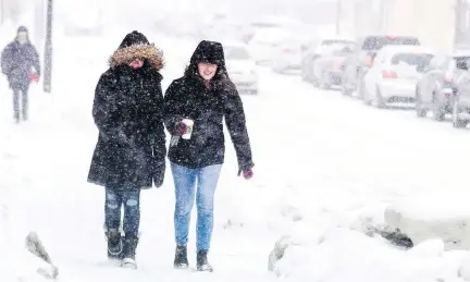  ?? ASHLEY FRASER ?? Two well bundled young women walk along Bank Street as Ottawa was hit with a heavy snowfall Sunday.