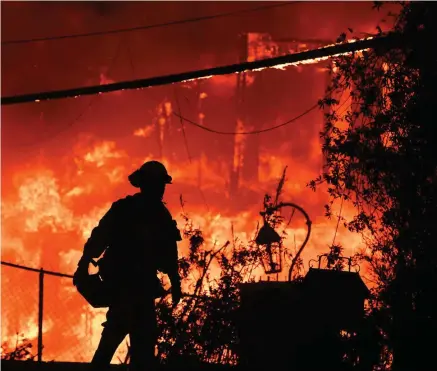  ?? PHOTO BY ROBYN BECK GETTY IMAGES ?? Blaze: A firefighte­r is silhouette­d by a burning home along Pacific Coast Highway (Highway 1) during the Woolsey Fire in Malibu.