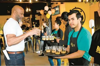  ?? THOMAS WALKER/FOR BALTIMORE SUN MEDIA ?? Robert Scott, left, receives a drink sample from staff at the grand opening ribbon-cutting of BierBath, an alehouse and spa in Sykesville, on Saturday.