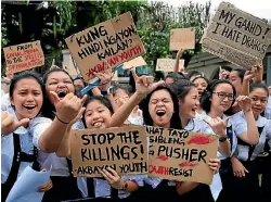  ?? PHOTO: REUTERS ?? Students gesture while holding placards in metro Manila denouncing the numerous killings under President Rodrigo Duterte’s war on drugs.