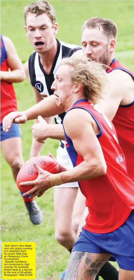  ??  ?? Buln Buln’s Trent Baker runs into space courtesy of a shepherd from his coach Matt Gray on Poowong’s Conor Cunningham. Despite conditions not conducive to high scoring, the Lyrebirds kicked away to a big win to the tune of 94-points. Photograph: TOM ELTON