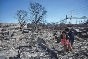  ?? MATTHEW THAYER/THE MAUI NEWS VIA AP PATRICK T. FALLON/AFP VIA GETTY IMAGES ?? Davilynn Severson and Hano Ganer look for belongings amid the ashes of their family’s home in the aftermath of a wildfire in Lahaina, western Maui, Hawaii on Aug. 11. Brushfires on Maui, fueled by high winds from Hurricane Dora passing to the south, broke out on Aug. 8 and rapidly engulfed Lahaina. More than 100 bodies have been recovered, and hundreds more people are still missing. There is a huge need for assistance for the wildfire’s survivors.