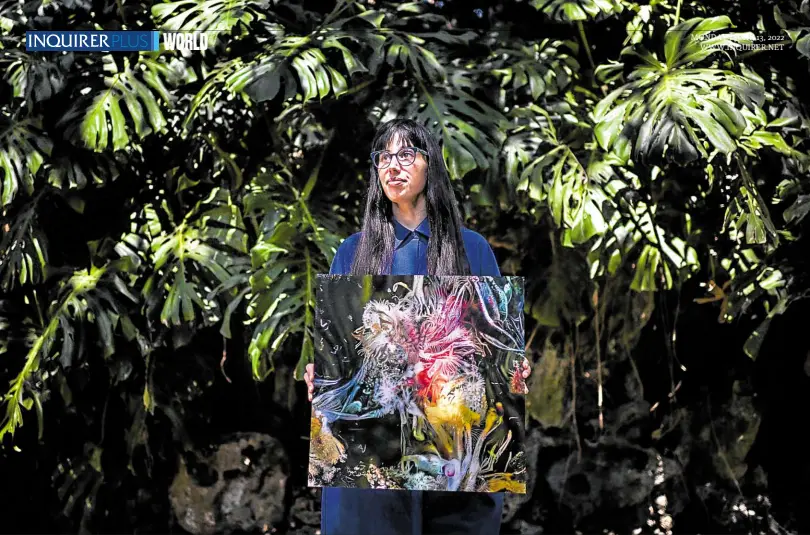  ?? —PHOTOS BY AFP ?? COMPUTER AIDED Argentinia­n artist Sofia Crespo holds one of her works on June 8. Crespo, who creates her works with the help of artificial intelligen­ce, is part of the “generative art” movement, where humans create rules for computers which then use algorithms to generate new forms, ideas and patterns.