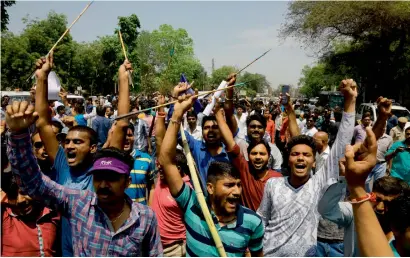  ?? AP ?? Dalits hold bow and arrows and shout slogans during a nationwide strike in Ahmedabad on Monday. —