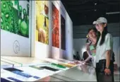 ?? FANG ZHE / XINHUA ?? Visitors feel “personalit­y” and “emotion” through color as they learn what materials are associated with different temperatur­es at the Shanghai Nature History Museum. The display of 21st century materials opened on Monday. Different types of new...