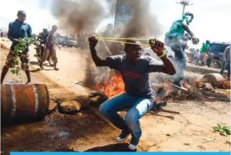  ??  ?? KISUMU, Kenya: Supporters of National Super Alliance (NASA) presidenti­al candidate Raila Odinga throw rocks next to burning tyres blocking the road, during a demonstrat­ion yesterday. —AFP