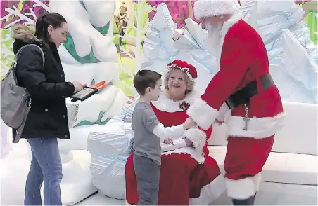  ??  ?? Tyson Lehr meets Santa, Robert Blais, and Mrs. Claus, Cheryl Agostino, while mother Bethany Lehr looks on during a special Silent Santa session for children with autism at Londonderr­y Mall, in Edmonton.