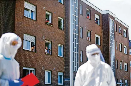  ?? REUTERS ?? Mitarbeite­r der Tönnies-Fabrik stehen in einem Wohnhaus unter Quarantäne. Die Platzverhä­ltnisse sollen dort prekär sein.