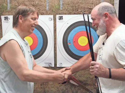  ?? PAUL A. SMITH ?? Archery instructor Lyle Maryniak of Wauwatosa, right, congratula­tes Tony Jandrowski of Milwaukee after Jandrowski, who is blind, shot a tight three-arrow group during a program at West Town Archery in Brookfield.