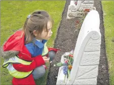  ??  ?? n MEMORIAL: A pupil from Harefield Infant School at one of the war graves at St Mary’s Church