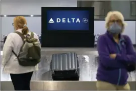  ?? MICHAEL DWYER — THE ASSOCIATED PRESS ?? Passengers wait for luggage in the arrival area of Delta Air Lines at Logan Internatio­nal Airport last July in Boston. Delta said Wednesday that travel demand is improving after flattening out in late summer, when coronaviru­s cases spiked in the U.S.