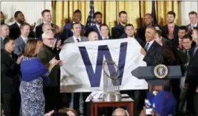  ?? PABLO MARTINEZ MONSIVAIS — THE ASSOCIATED PRESS ?? President Barack Obama holds up a ‘W’ flag signed by the Cubs during a ceremony in the East Room of the White House in Washington, Monday where the president honored the 2016 World Series champions. On the far left are Cubs co-owner Laura Ricketts, and...