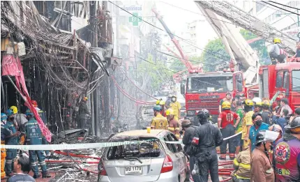  ?? APICHART ?? Fire engines and crew from Suan Mali rescue station, along with volunteers, begin clearing up the area after a fire engulfed four commercial buildings on Ratchawong Road. The incident killed two people and injured 11.