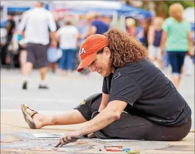  ?? CARRIE GARLAND — THE NEWS-HERALD ?? Lori Kavanaugh Lewarski creates a design using chalk at the 2017 Willoughby ArtsFest on July 15.