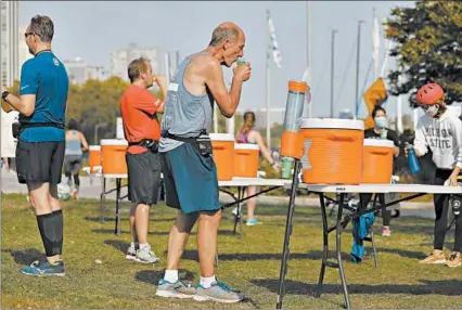  ?? ABEL URIBE/CHICAGO TRIBUNE ?? Runners stop at a Chicago Area Runners Associatio­n water station Saturday near Belmont Harbor.
