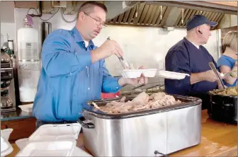  ?? LYNN KUTTER ENTERPRISE-LEADER ?? Robert Raines of Lincoln fills to-go plates with smoked turkey. Burger Land gave away about 500 free Thanksgivi­ng dinners on Thursday.