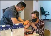  ??  ?? Jose Alfredo Cabrera, right, receives his COVID-19 vaccinatio­n from Kaiser nurse Romel Labrajo.