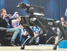  ?? Associated Press file ?? A Boston Dynamics SpotMini robot walks through a conference room during a robotics summit in Boston in May. For nine years, the secretive firm has unnerved viewers with YouTube videos of robots that jump, gallop or prowl like animals.