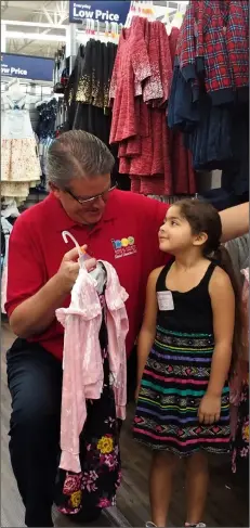  ?? PHOTO TOM BODUS ?? salvation army el Centro Corps board member and back to school program volunteer Kurt Leptich assists 6-year-old ben hulse elementary student belinda bell with a new dress she’d been eyeing since her previous trip to Walmart.