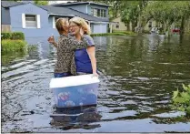  ?? DEDE SMITH /THE FLORIDA TIMES-UNION ?? Homeowners in Jacksonvil­le embrace as they rescue belongings from flooded houses during Hurricane Irma. The storm caused damage to homes, businesses and several beaches on Florida’s Atlantic Coast.